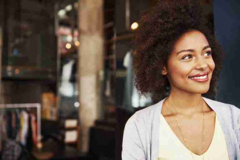 Smiling ethnic woman standing outside coffee house